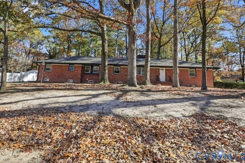 Single-story residence featuring a classic red brick exterior, a low-pitch roofline, and mature deciduous trees