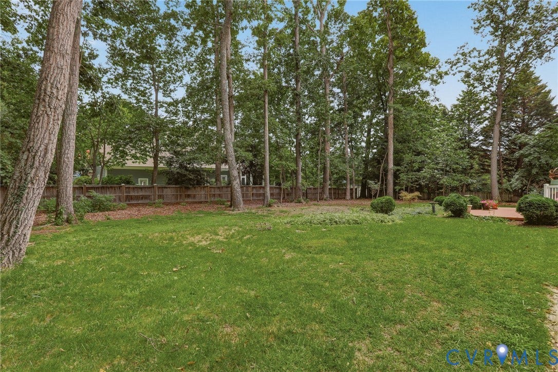 2311 Castle Hill Road, Midlothian, VA 23113 Expansive backyard featuring a lush grass lawn, mature trees, wood privacy fencing, and a brick patio