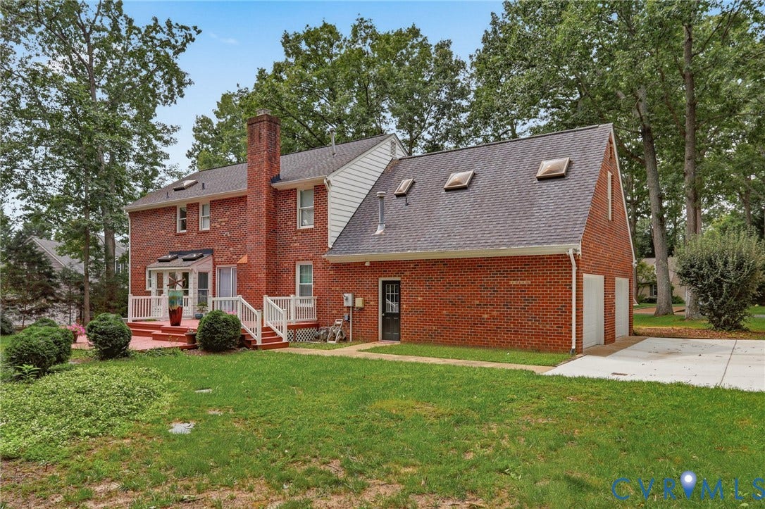 2311 Castle Hill Road, Midlothian, VA 23113 Brick exterior featuring a multi-gabled roofline, three roof-mounted skylights, a raised wooden deck with railings, and an attached two-car garage