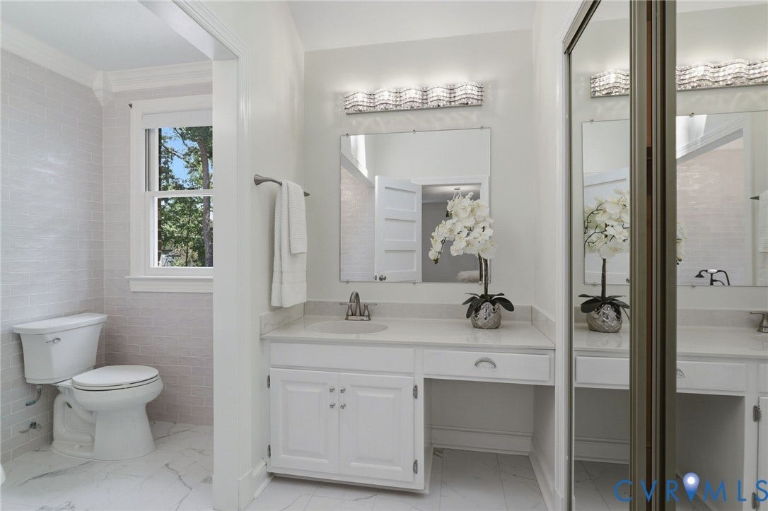 2311 Castle Hill Road, Midlothian, VA 23113 Bathroom featuring a vanity with integrated cabinetry, solid-surface countertop, rectangular mirror, multi-bulb wall lighting, and large-format tile flooring