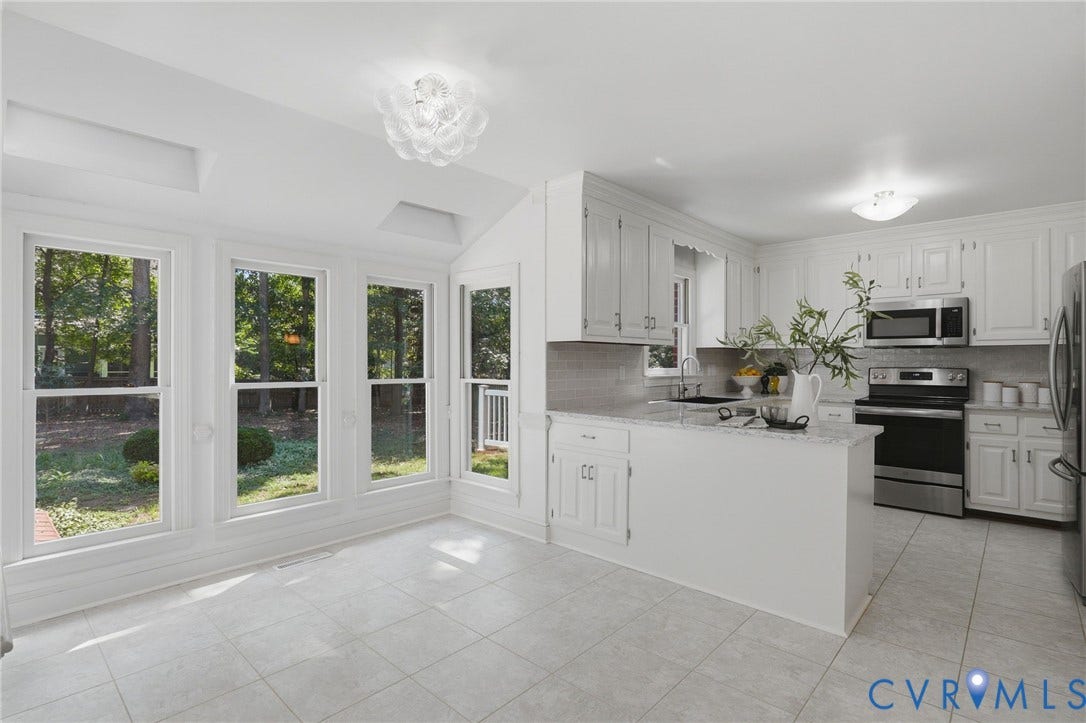 2311 Castle Hill Road, Midlothian, VA 23113 Kitchen featuring white cabinetry, light-toned stone-finish countertops, stainless steel appliances, large-format tile flooring, and multiple floor-to-ceiling windows