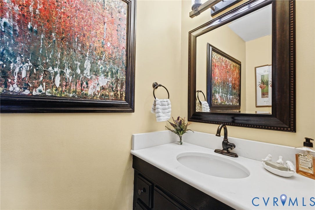13908 Pagehurst Terrace, Salisbury, Midlothian, VA 23113 Vanity featuring dark-finish cabinetry, a white stone-surface countertop, an undermount oval sink, an oil-rubbed bronze faucet, and a coordinating framed mirror