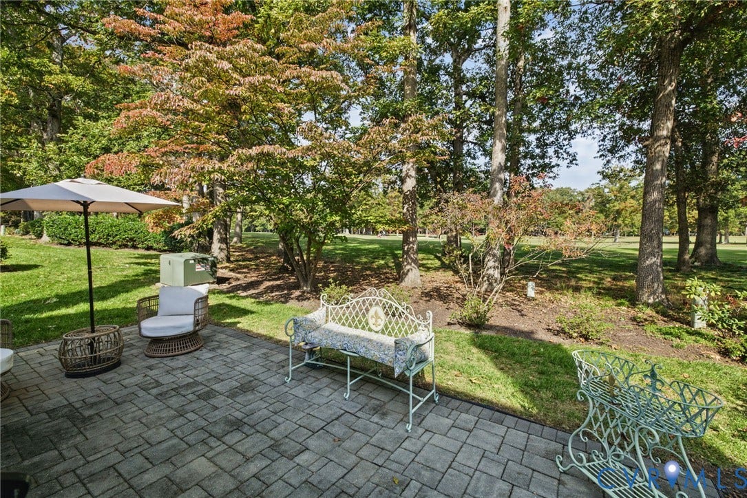 13908 Pagehurst Terrace, Salisbury, Midlothian, VA 23113 Paver patio featuring a grey rectangular stone pattern, surrounded by a landscaped lawn and mature tree canopy with golf course views