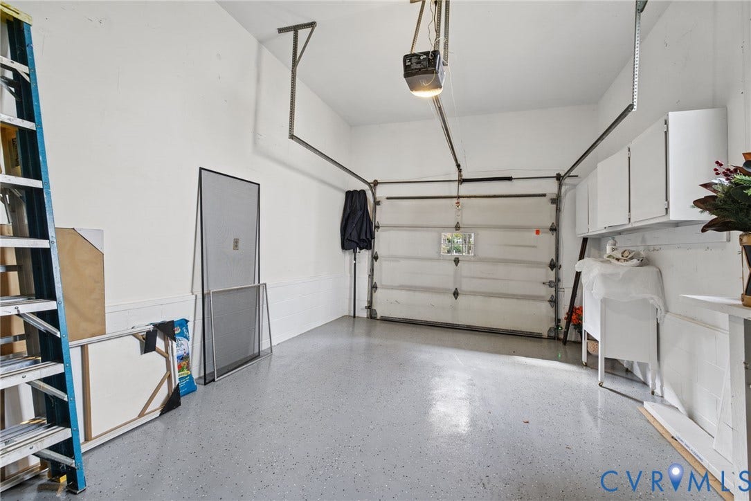 13908 Pagehurst Terrace, Salisbury, Midlothian, VA 23113 Attached garage featuring a durable epoxy concrete floor, white wall-mounted storage cabinetry, and an overhead door mechanism