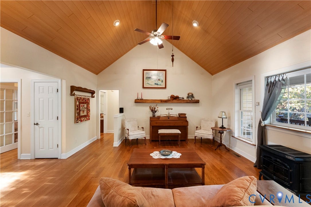 Vaulted tongue-and-groove wood ceiling, polished wood flooring, built-in wooden mantel, recessed lighting, and black wood-burning stove