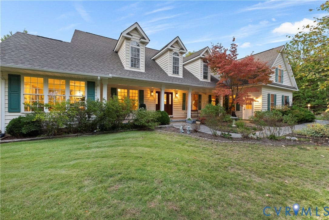Multi-gabled exterior featuring horizontal siding, dormer windows, shuttered multi-pane windows, and an expansive front porch with structural columns