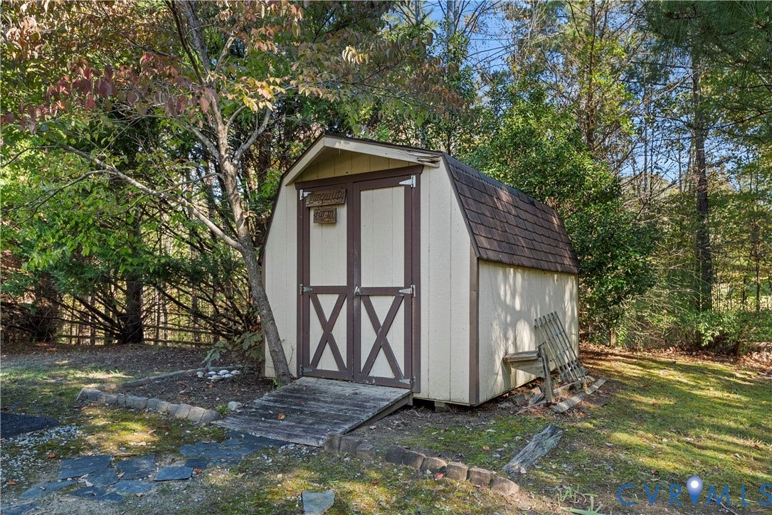 Outbuilding featuring a gambrel roof, double-door entry, and an attached wood-slat ramp