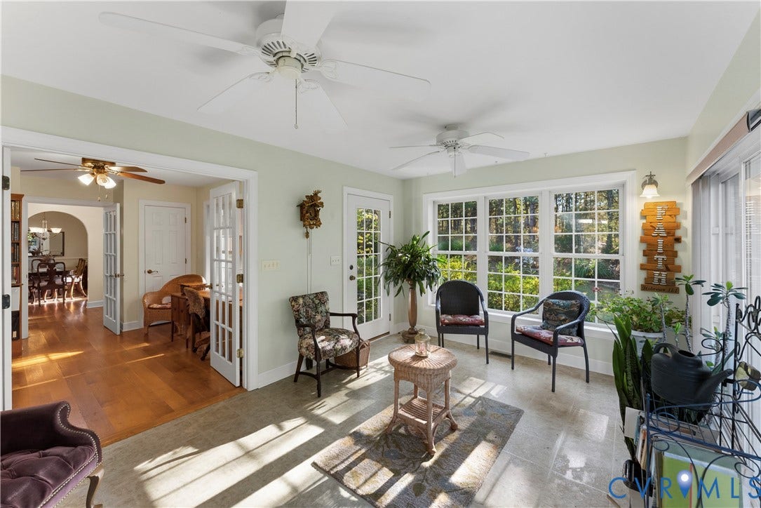 Sunroom featuring neutral tile flooring, expansive multi-pane windows, dual ceiling fans, and a glass-paneled exterior door