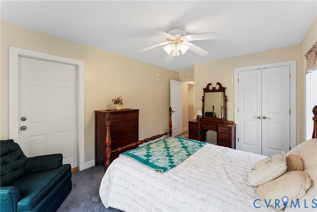 Neutral-toned walls featuring a multi-blade ceiling fan with integrated light fixture, carpeted flooring, and two sets of interior white panel doors