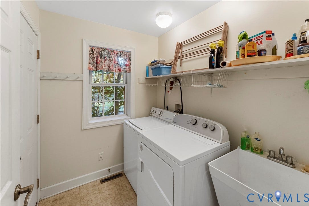 Laundry room featuring a single-hung window, utility sink with a chrome faucet, wall-mounted open shelving, and wall-mounted garment rack