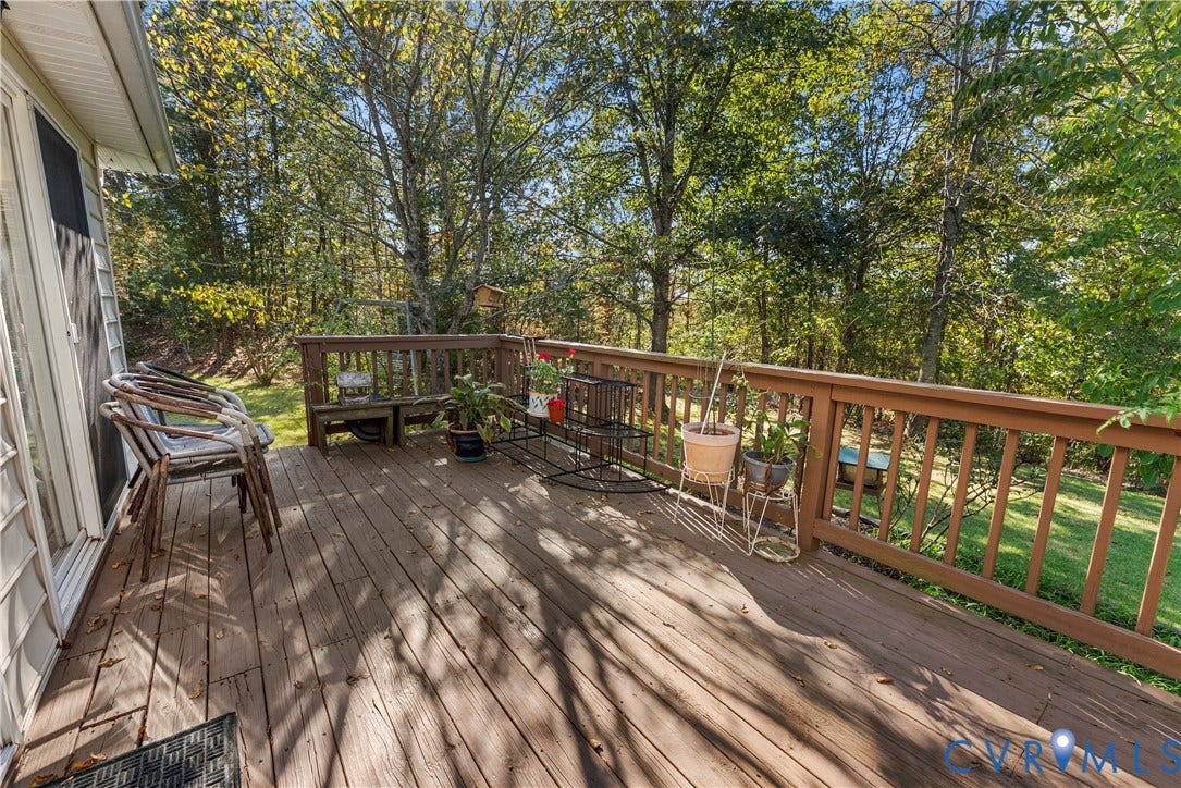 Elevated wood deck featuring vertical wood balusters and a sloped rear yard with mature trees