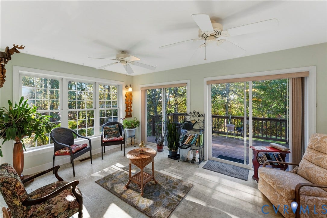 Sunroom featuring tile flooring, dual ceiling fans, large grid-pane windows, and two sets of sliding glass doors