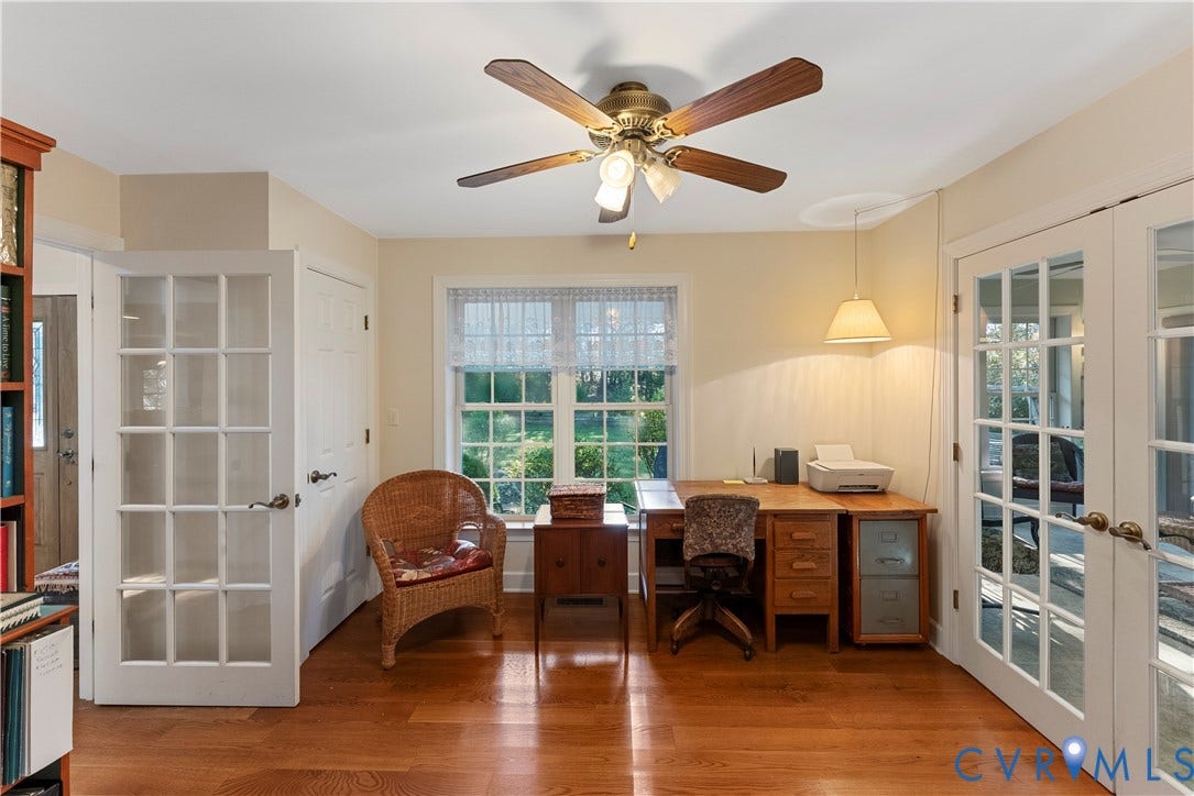 Wood-finish flooring, central ceiling fan with integrated lighting, multi-pane glass French doors, and multi-pane window with custom valance