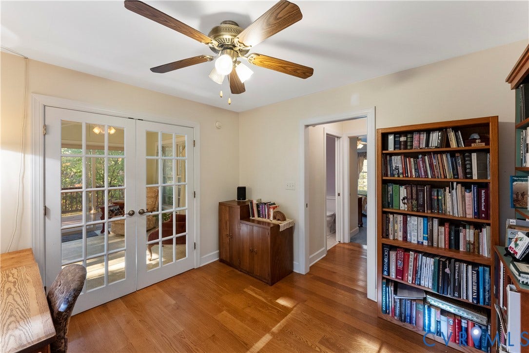 Room featuring wood-finish flooring, white French doors with glass panes, and a ceiling fan with integrated lighting