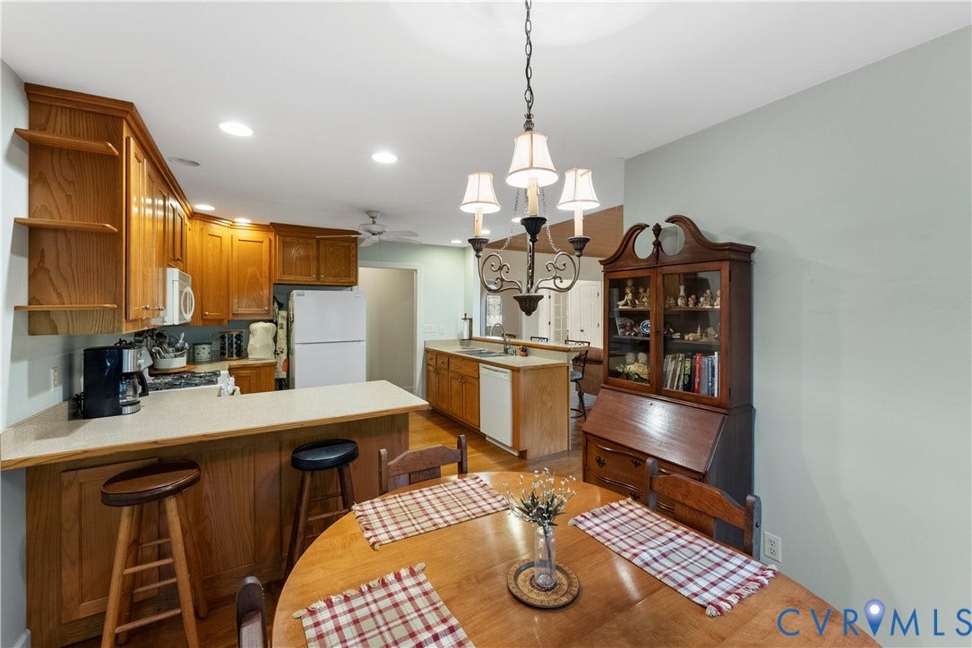 Kitchen featuring wood cabinetry, solid-surface countertops, a peninsula with bar seating, and a decorative multi-arm chandelier