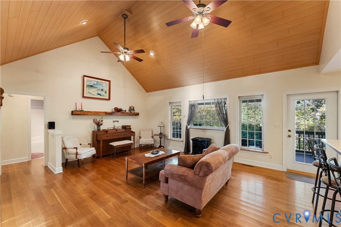 Vaulted ceilings with wood-plank paneling, wood-finish flooring, recessed lighting, dual ceiling fans, and a custom wood floating mantel