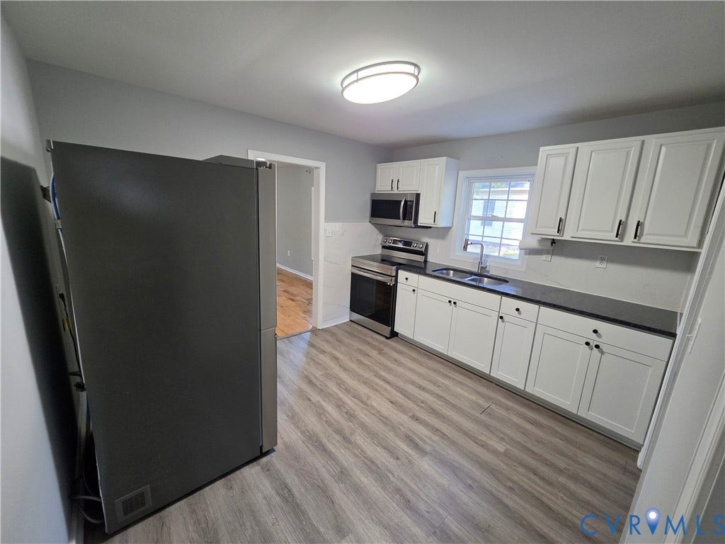 2406 Trenton Street, Hopewell, VA 23860 Kitchen featuring white shaker-style cabinetry, dark solid-surface countertops, stainless steel appliances, and wood-finish flooring