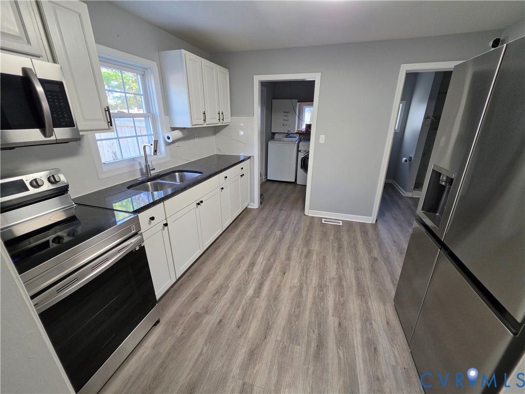 2406 Trenton Street, Hopewell, VA 23860 Kitchen featuring white shaker-style cabinetry, stainless steel appliances, dark countertops with a dual-basin sink, and wood-finish flooring