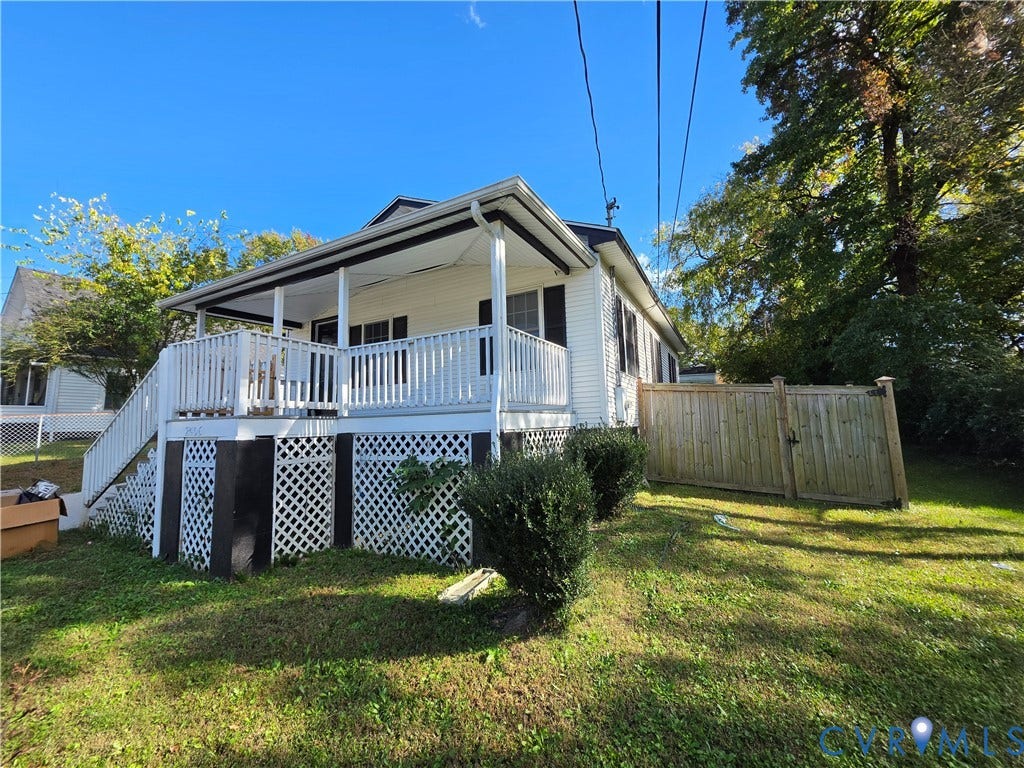 2406 Trenton Street, Hopewell, VA 23860 Exterior featuring light-colored horizontal siding, a raised deck with white railing, decorative lattice skirting, and a wood privacy fence