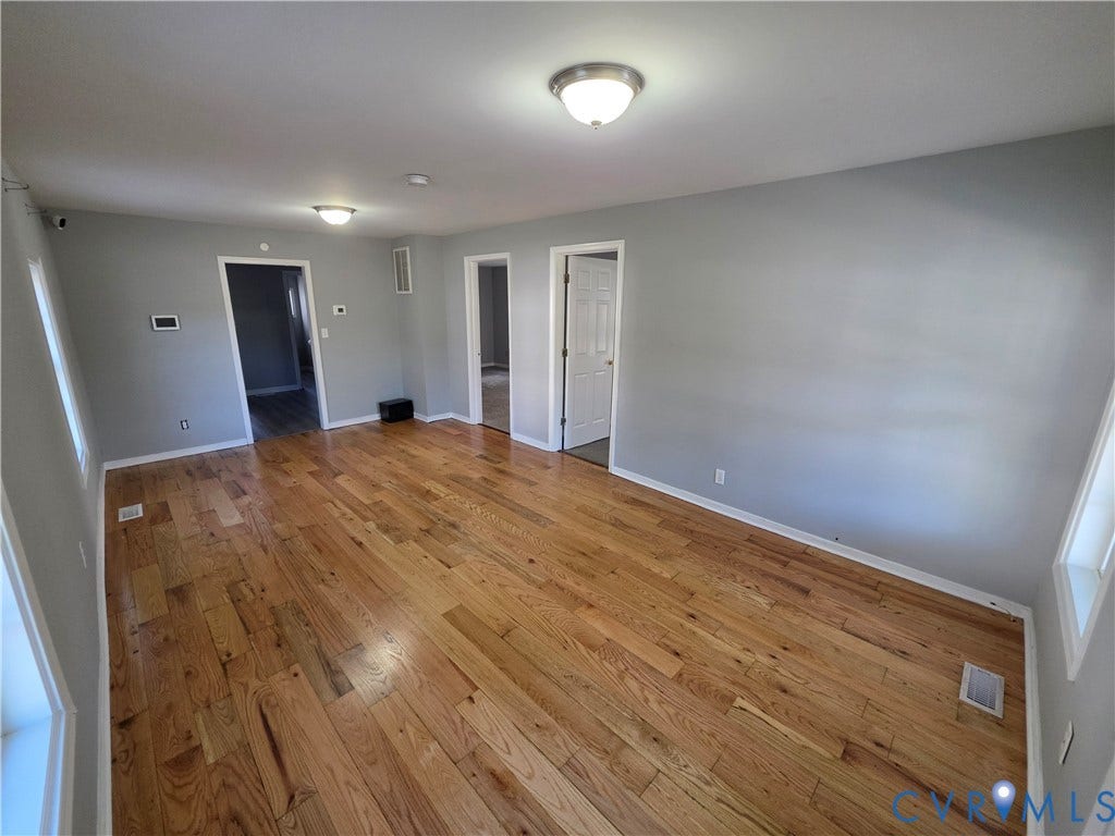 2406 Trenton Street, Hopewell, VA 23860 Interior room featuring wood-finish flooring, neutral wall paint, and two flush-mount ceiling light fixtures