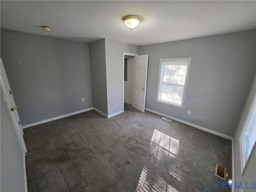 2406 Trenton Street, Hopewell, VA 23860 Neutral-toned interior space featuring wall-to-wall carpeting, grey-painted walls, a multi-pane window, and a white six-panel door