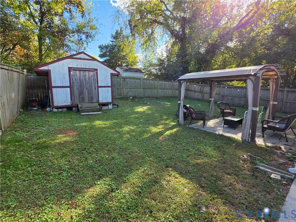 2406 Trenton Street, Hopewell, VA 23860 Backyard featuring a wood-sided storage shed, wood privacy fencing, and a permanent metal-frame pergola over a paved patio