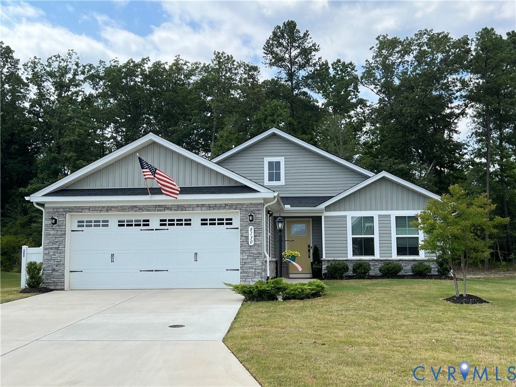 8130 W Danube Loop, Autumn Pines, New Kent, VA 23124 Single-story exterior featuring a stone veneer facade, horizontal and vertical lap siding, a two-car garage with transom windows, and an expansive concrete driveway