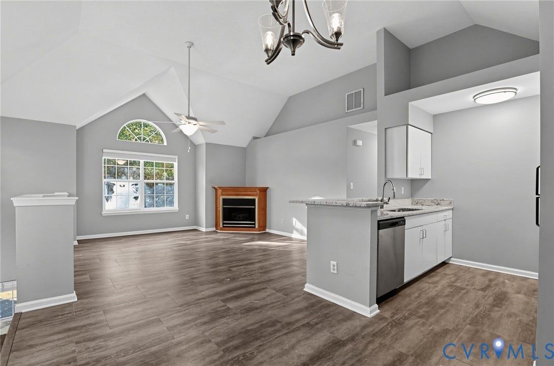 910 Rue Marseille, Les Chateaux, Chesapeake, VA 23320 Vaulted ceilings, wood-finish flooring, corner fireplace with wood mantle, and kitchen area featuring white cabinetry with stone-finish countertops