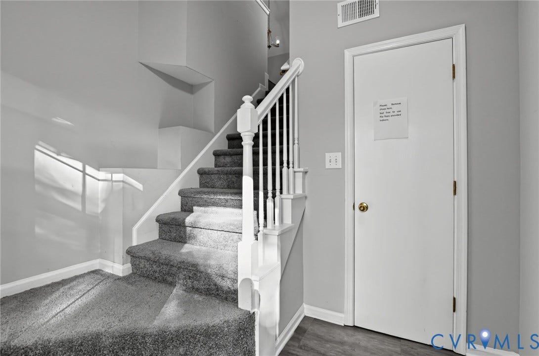 910 Rue Marseille, Les Chateaux, Chesapeake, VA 23320 Staircase featuring a white wooden balustrade and neutral-toned carpeting, complemented by a solid core door and wood-finish flooring