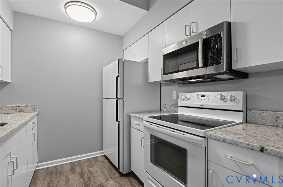 910 Rue Marseille, Les Chateaux, Chesapeake, VA 23320 Kitchen featuring white cabinetry, stone-surface countertops, wood-finish flooring, and stainless steel microwave
