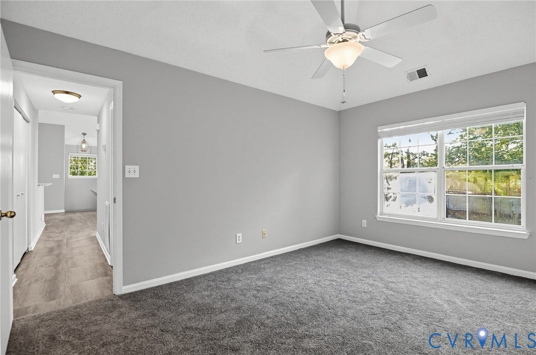 910 Rue Marseille, Les Chateaux, Chesapeake, VA 23320 Neutral wall finishes, neutral carpeting, ceiling fan with integrated light fixture, and large-pane window with horizontal blinds