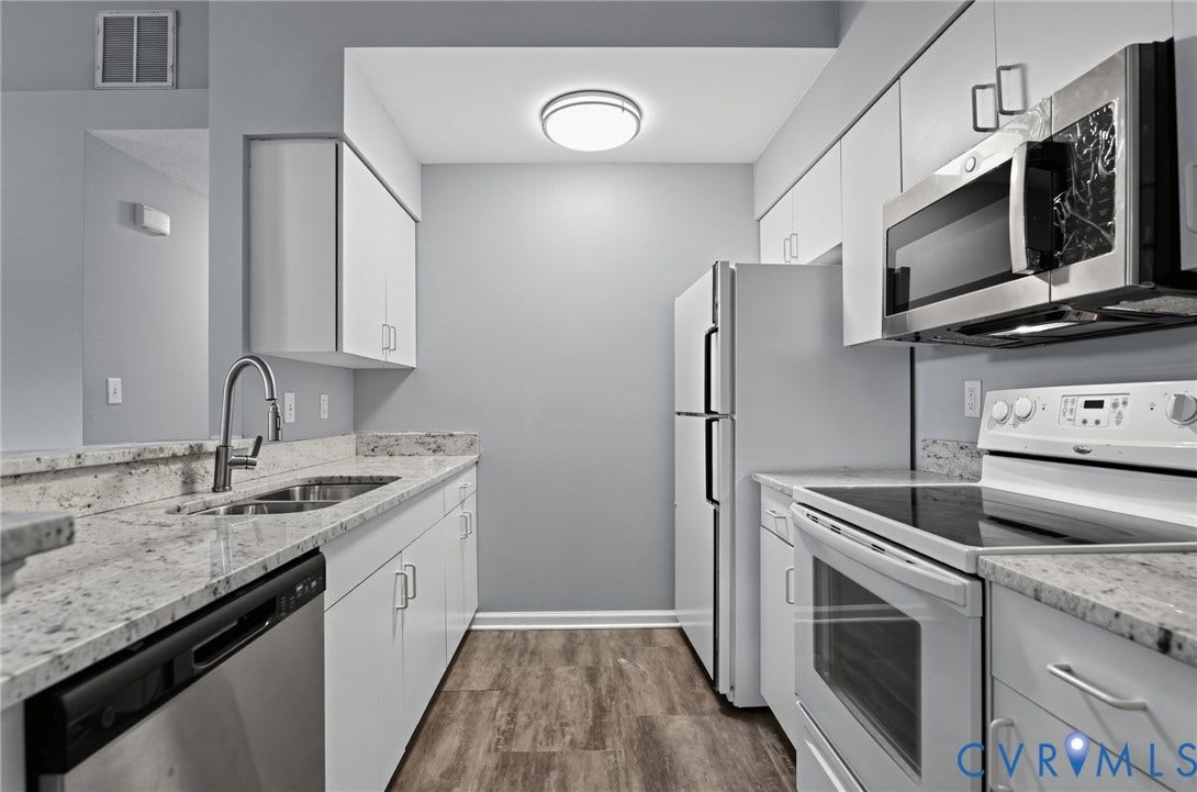 910 Rue Marseille, Les Chateaux, Chesapeake, VA 23320 Kitchen featuring stone-finish countertops, stainless steel appliances, wood-finish flooring, white cabinetry, and an under-mount double-basin sink with a gooseneck faucet