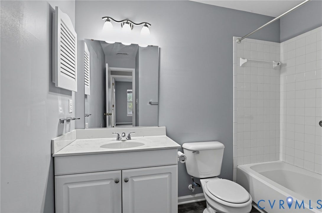 910 Rue Marseille, Les Chateaux, Chesapeake, VA 23320 Bathroom featuring a white vanity cabinet with an integrated sink, stone-composite countertop, three-light fixture, wall-mounted shuttered cabinet, and a shower-tub combination with white tile surround