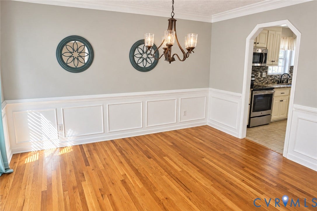 4229 Cedar Creek Lane, Prince George, VA 23875 Dining area featuring wood-finish flooring, white picture frame wainscoting, an arched doorway, and a multi-arm metal chandelier