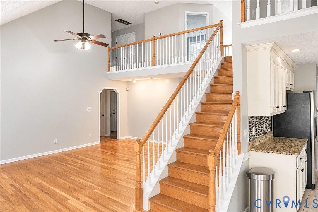4229 Cedar Creek Lane, Prince George, VA 23875 Vaulted ceiling, wood-finish flooring, staircase with a wood handrail and white balusters, overhead ceiling fan, and built-in cabinetry with a stone-finish countertop