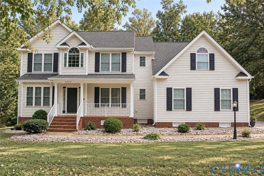 4229 Cedar Creek Lane, Prince George, VA 23875 Two-story residence featuring light-colored horizontal siding, a brick-foundation facade, an arched window detail, decorative shutters, and an elevated front porch