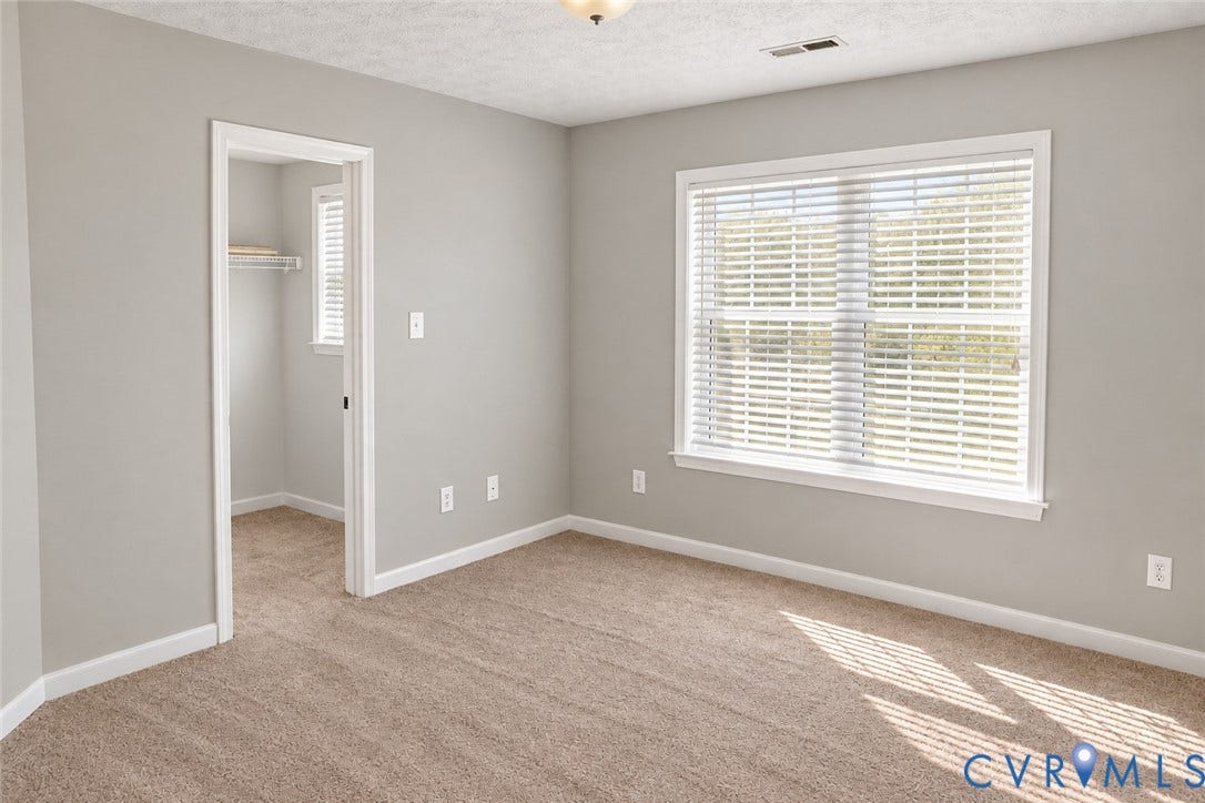 4229 Cedar Creek Lane, Prince George, VA 23875 Neutral-toned interior walls featuring wall-to-wall carpeting, a large window with horizontal blinds, and a walk-in closet with built-in shelving