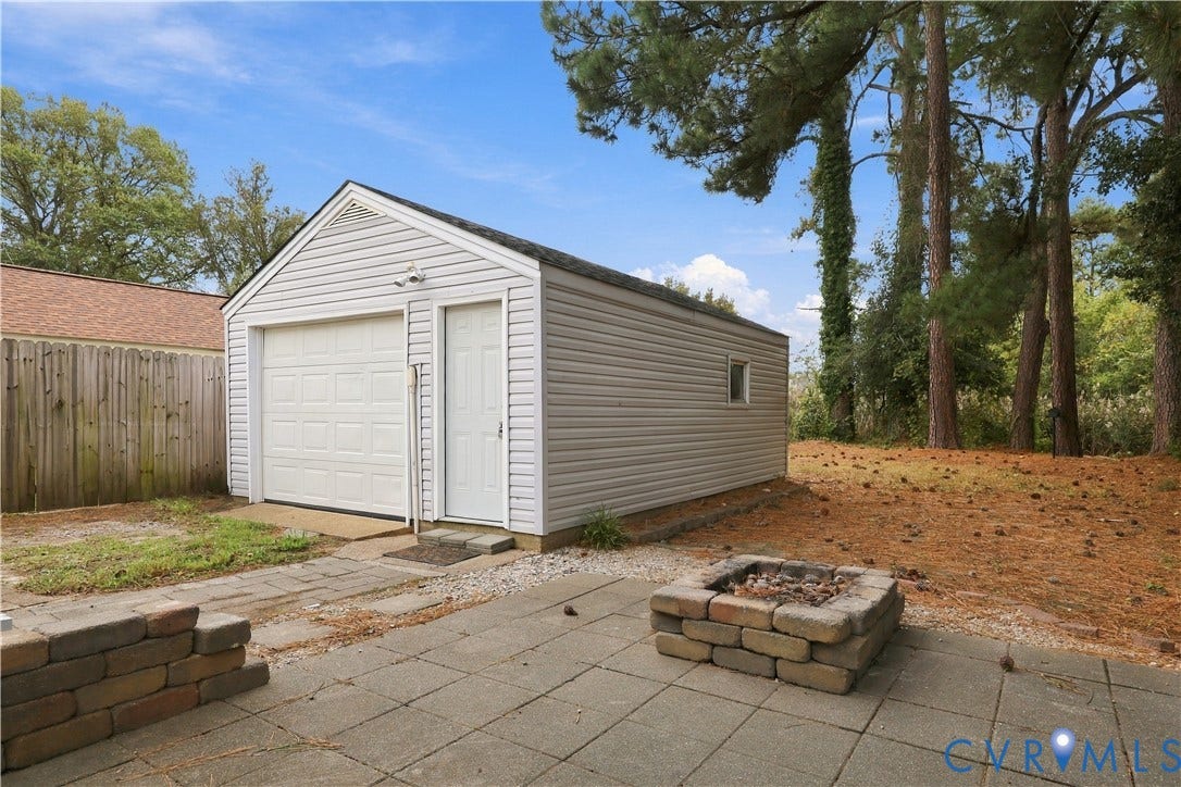 305 Arizona Street, Kingman Heights, Portsmouth, VA 23701 Detached single-car garage featuring vinyl siding, a paved patio, and a stone-style fire pit