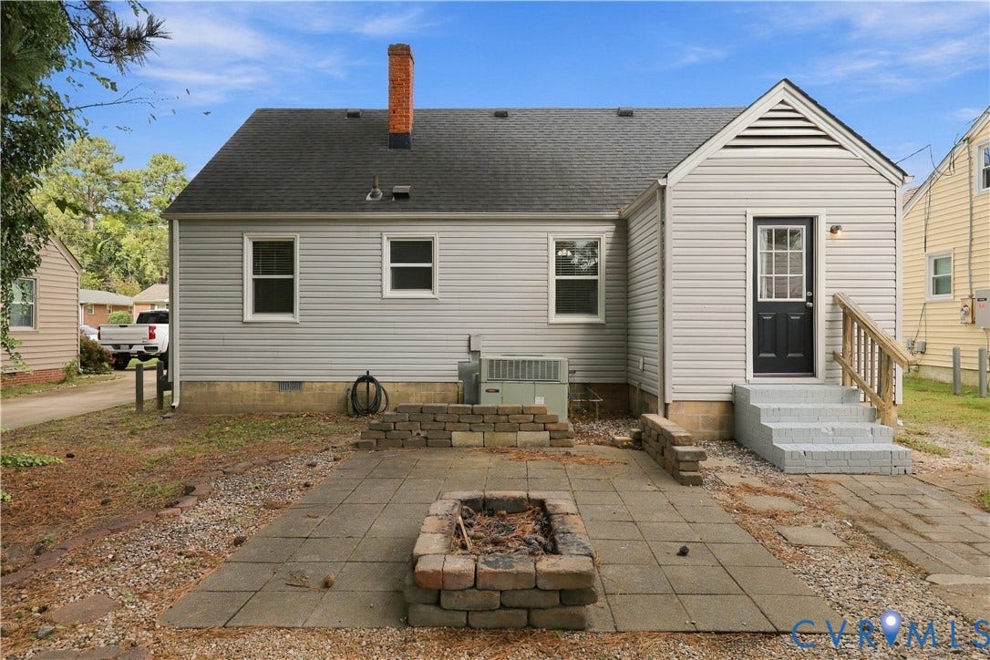 305 Arizona Street, Kingman Heights, Portsmouth, VA 23701 Exterior of home featuring vinyl siding, a brick chimney, a stone paver patio, and a built-in stone fire pit