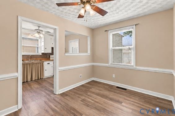 305 Arizona Street, Kingman Heights, Portsmouth, VA 23701 Room featuring wood-finish flooring, chair rail molding, a ceiling fan with integrated light fixture, and an interior pass-through opening