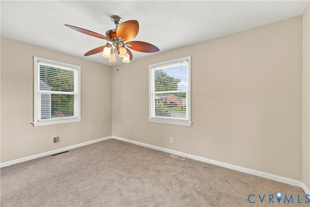 305 Arizona Street, Kingman Heights, Portsmouth, VA 23701 Neutral-toned interior featuring carpeting, a multi-blade ceiling fan with integrated lighting, and dual windows with horizontal blinds
