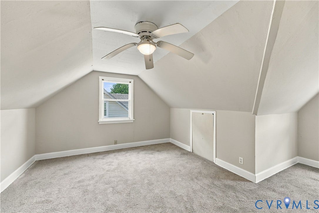 305 Arizona Street, Kingman Heights, Portsmouth, VA 23701 Vaulted ceilings featuring a central white ceiling fan with integrated lighting, neutral wall finishes, plush wall-to-wall carpeting, a single-pane window, and an integrated access panel for attic storage