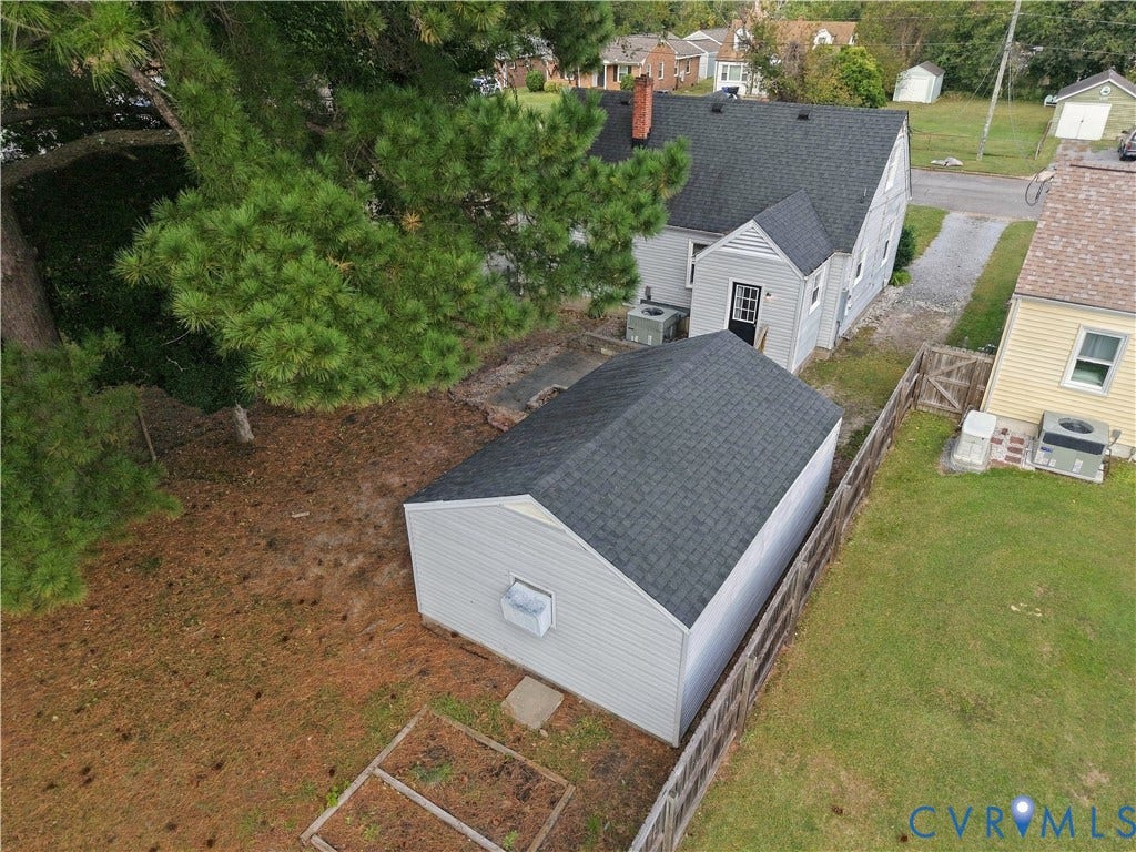 305 Arizona Street, Kingman Heights, Portsmouth, VA 23701 Exterior features include a detached garage with dark shingle roofing, a partial wood privacy fence, and a designated garden plot area