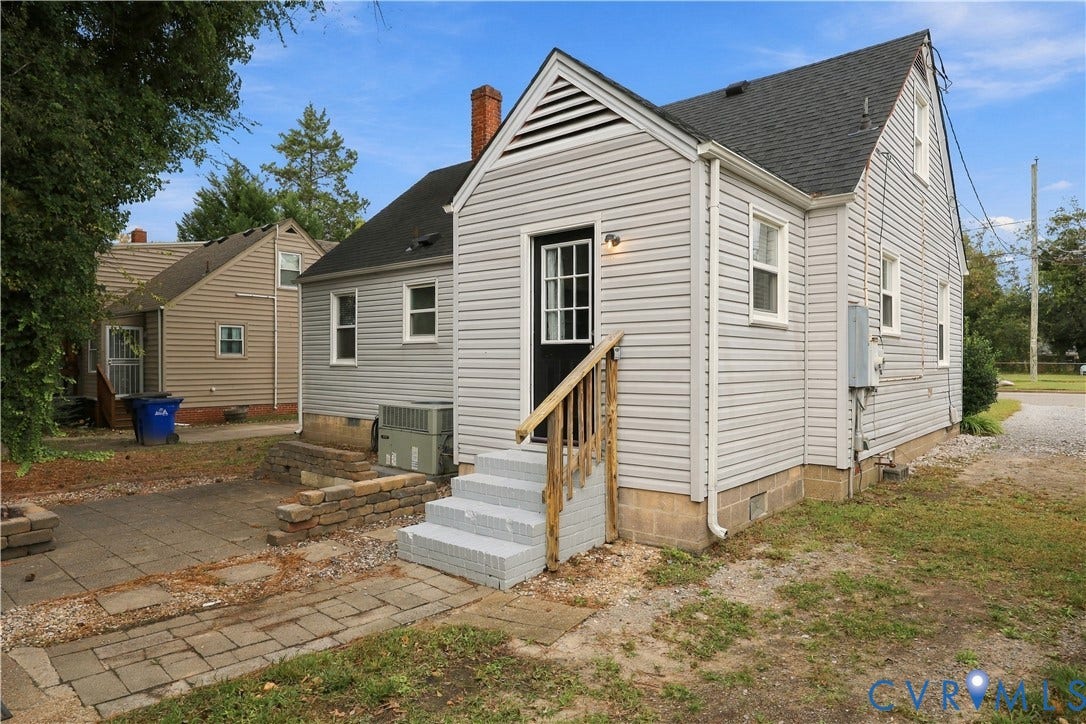 305 Arizona Street, Kingman Heights, Portsmouth, VA 23701 Light gray vinyl siding, gabled roof, paved stone patio, retaining wall, and exterior wooden stair railing