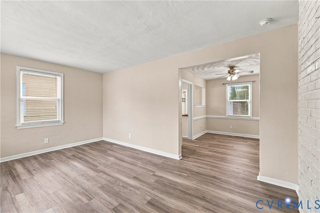 305 Arizona Street, Kingman Heights, Portsmouth, VA 23701 Living space featuring wood-finish flooring, painted brick wall, recessed wall opening, and multi-pane windows