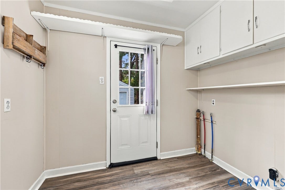 305 Arizona Street, Kingman Heights, Portsmouth, VA 23701 Utility room featuring wood-finish flooring, white overhead cabinetry, wall-mounted shelving, a wood-finish wall rack, and an exterior door with glass panes
