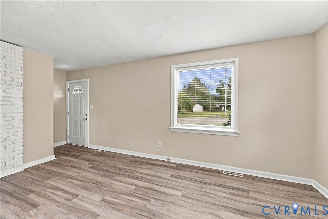 305 Arizona Street, Kingman Heights, Portsmouth, VA 23701 Living area featuring wood-finish flooring, a painted brick fireplace surround, and a single-lite paneled exterior door