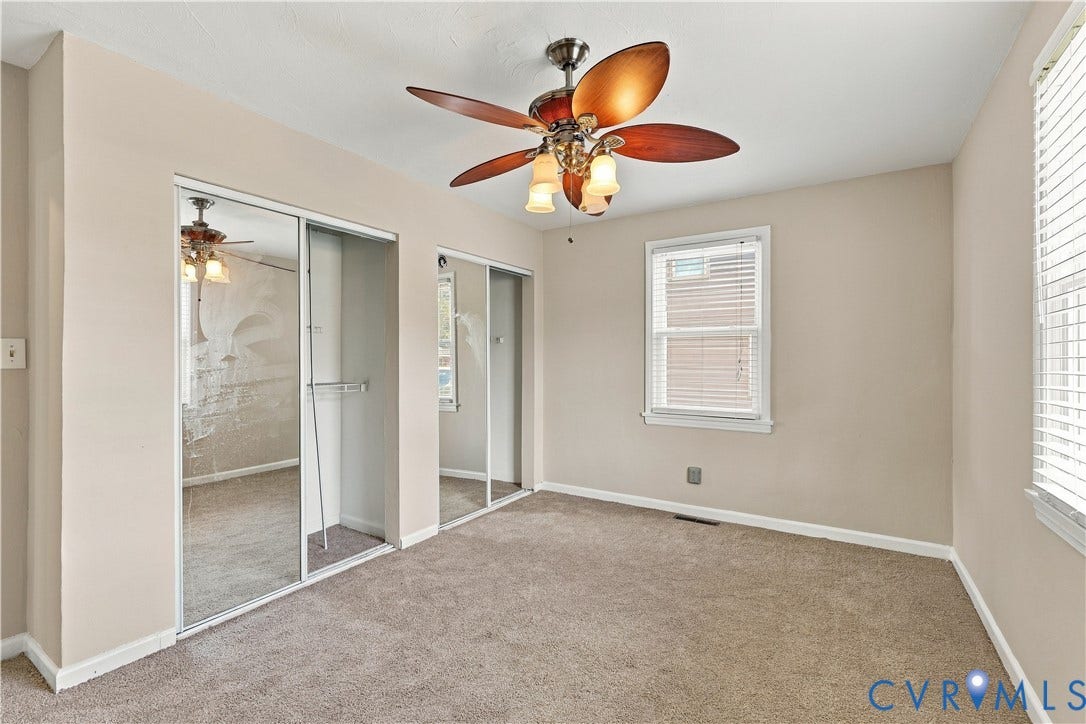 305 Arizona Street, Kingman Heights, Portsmouth, VA 23701 Room featuring neutral-toned carpeting, dual sliding mirror-paneled closet doors, a multi-blade ceiling fan with integrated lighting, and white horizontal window blinds