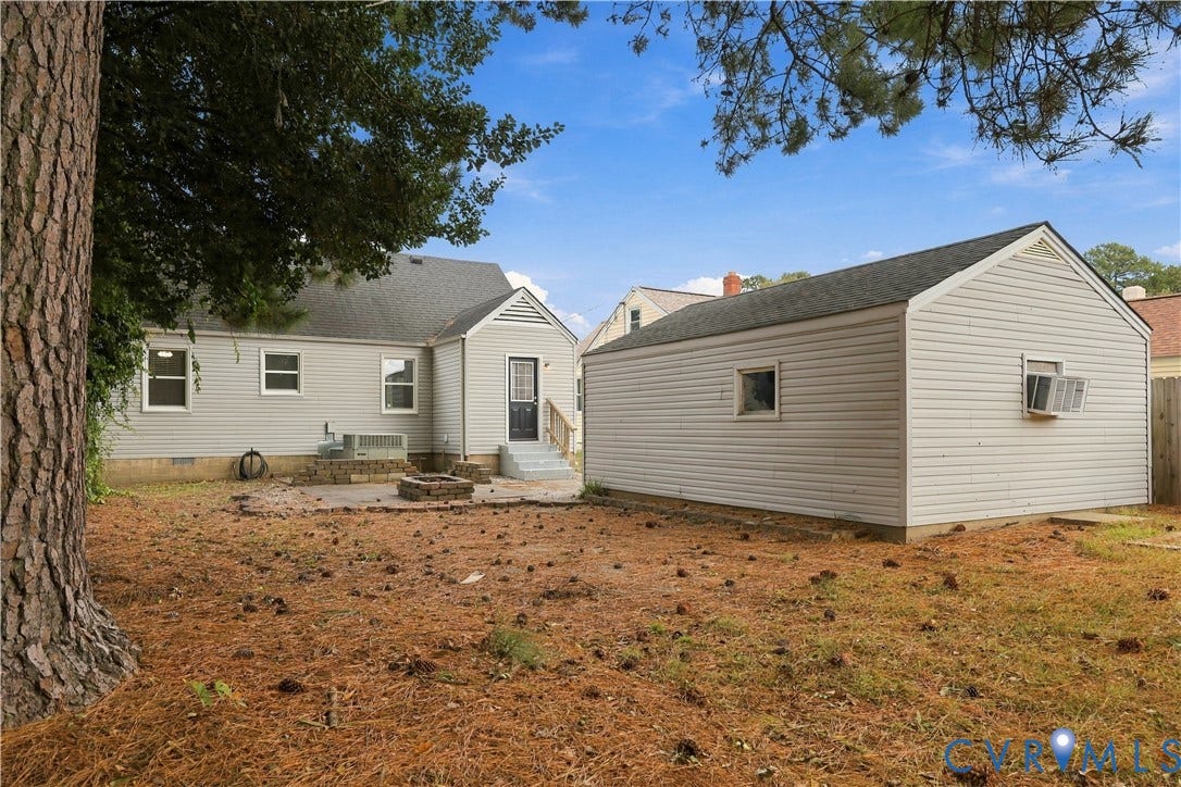 305 Arizona Street, Kingman Heights, Portsmouth, VA 23701 Exterior featuring light-gray horizontal siding, a detached garage, a stone fire pit, and mature pine trees