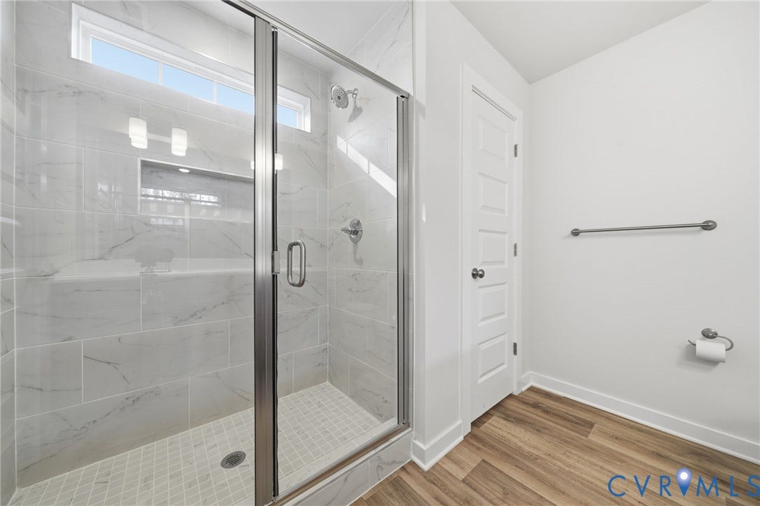 8209 Grantham Woods Way, Grantham Woods, Henrico, VA 23231 Walk-in shower featuring large-format stone-look wall tiles, a built-in recessed niche, clear glass enclosure, and wood-finish flooring